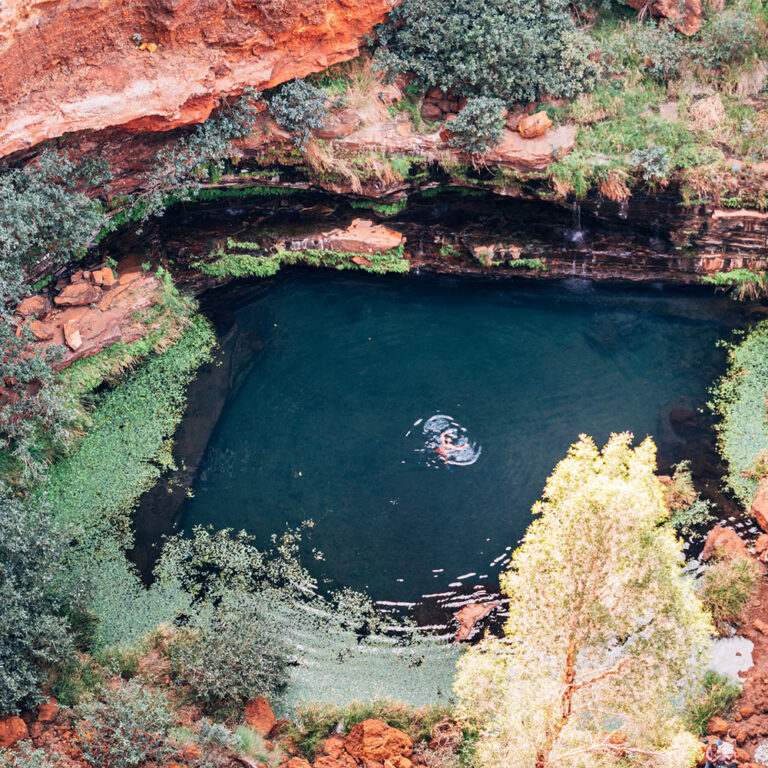 Natural swimming hole in the Australian outback with red rock formations and deep blue water